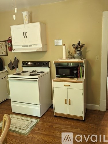 A small kitchen with a white stove and cabinets.