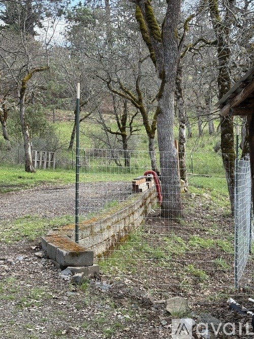 A fenced area with a red hose on a wooden post.