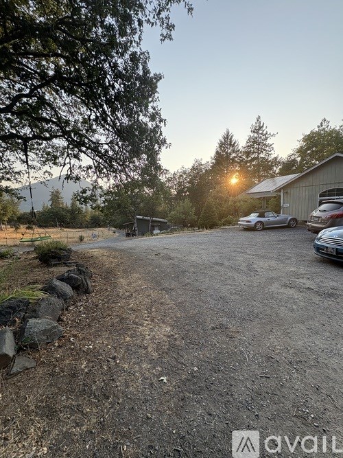 A gravel driveway leads to a house with a car parked in front.