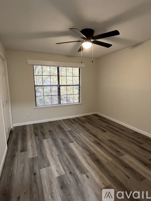 A room with a ceiling fan and wooden flooring.