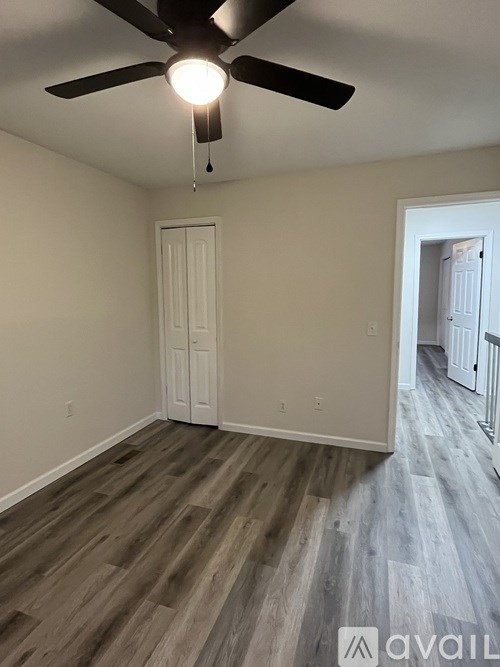 A room with a ceiling fan and wood flooring.