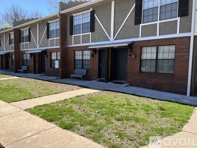 A row of apartment buildings with a grassy area in front.