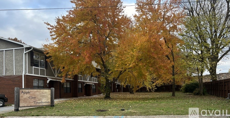 A sign that says Apple Glen Townhome sits in front of a building and trees.
