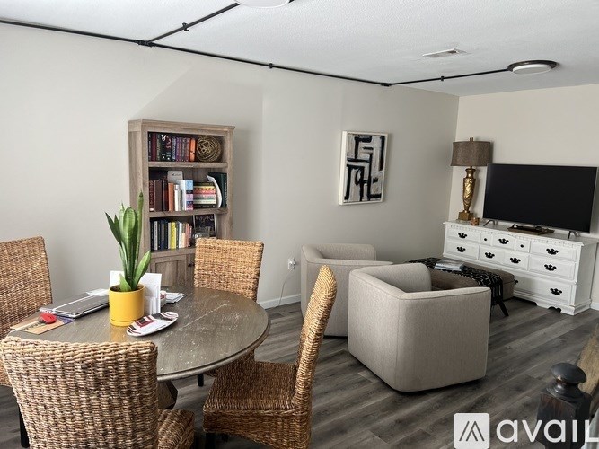 A living room with a dining table, chairs, a bookshelf, and a TV.