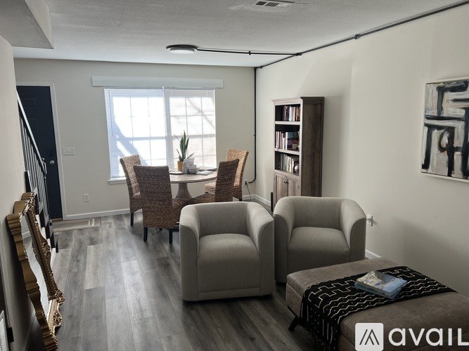 A living room with a grey sofa, a brown chair and a bookshelf.