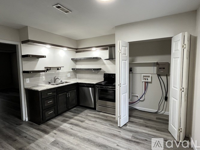 A modern kitchen with dark wood floors and stainless steel appliances.