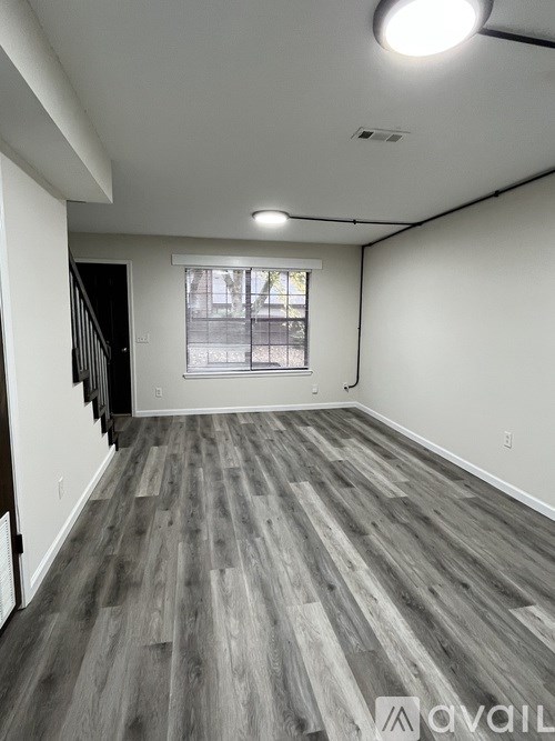 A room with wooden flooring and a window with blinds.