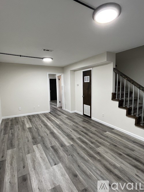 A room with a wooden floor and a staircase.