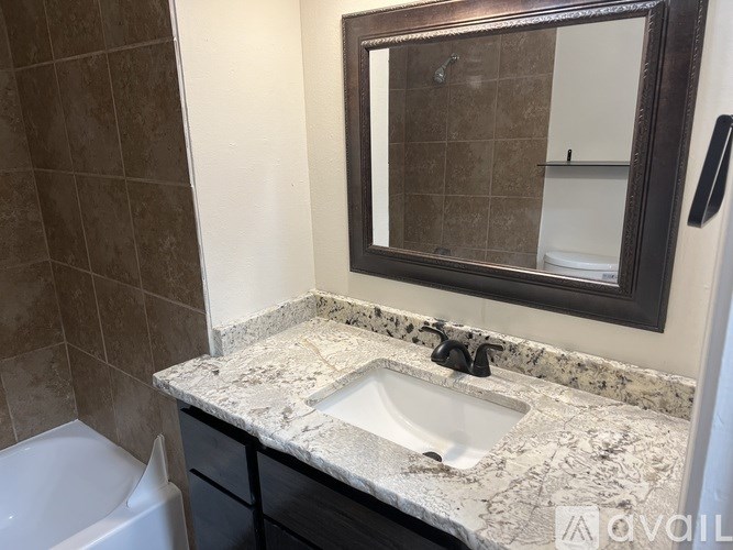 A bathroom with a marble countertop and a large mirror.