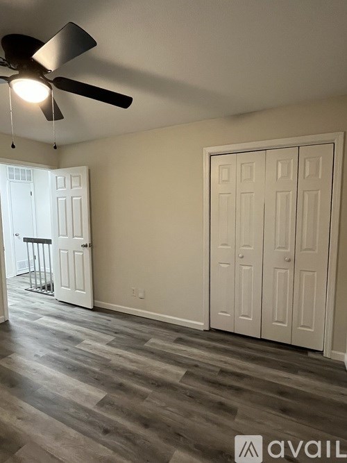 A room with a ceiling fan and a door on the right.