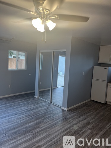 A room with a ceiling fan and a refrigerator.