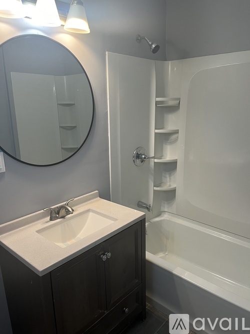 A bathroom with a sink, mirror, and bathtub.