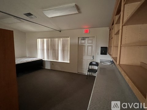A room with a bed, a chair, and a desk with a computer on it.