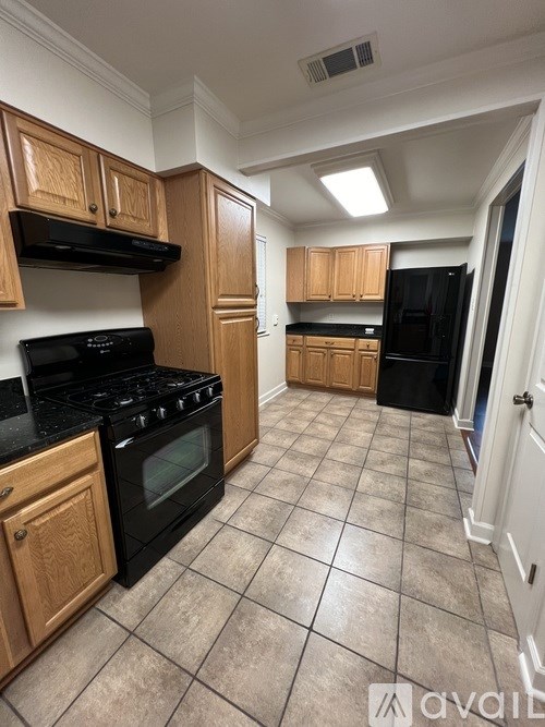A kitchen with black appliances and wooden cabinets.