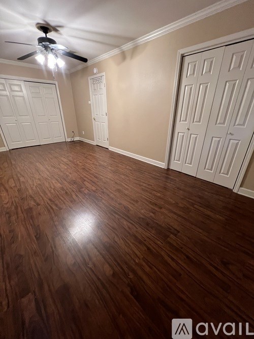 A room with a ceiling fan and wooden flooring.