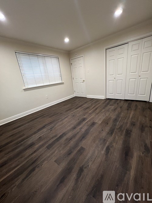 A room with wooden flooring and white walls.