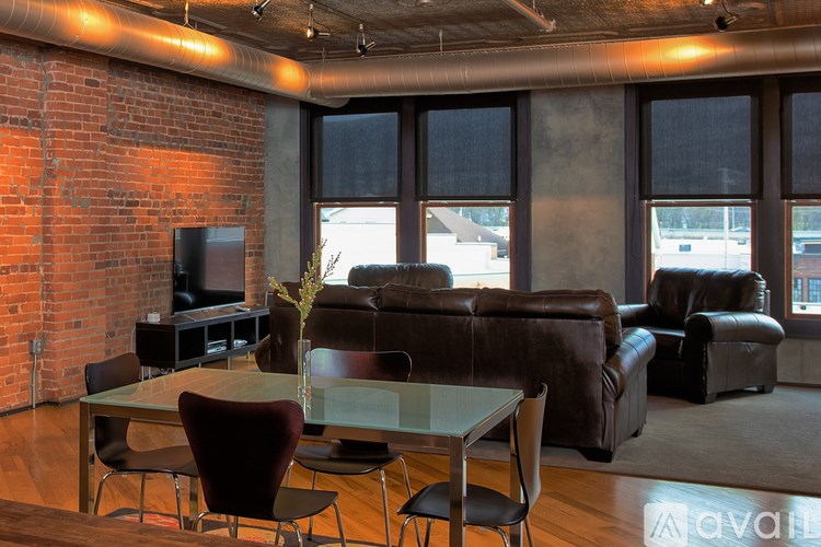A living room with a glass table and brown leather couches.