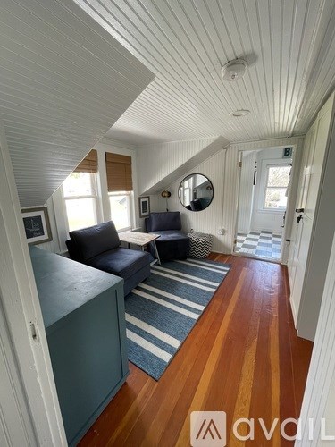 A living room with a blue couch and a wooden floor.