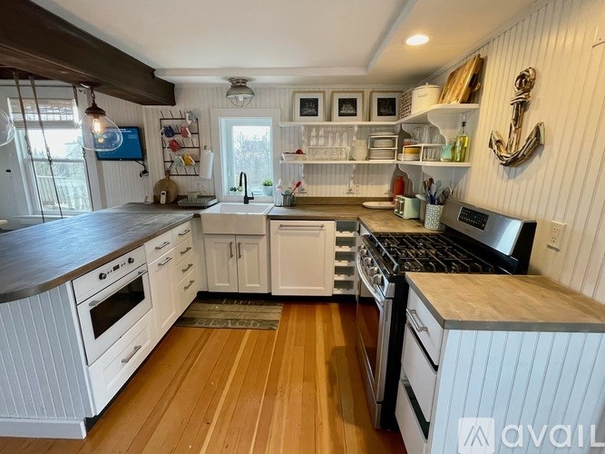 A kitchen with white cabinets and wooden floors.
