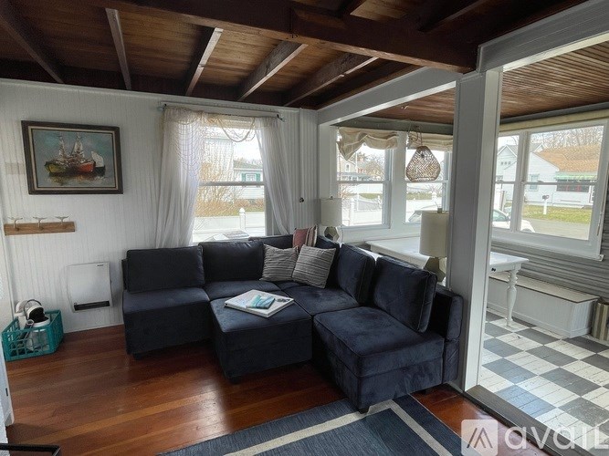 A blue couch with pillows sits in a room with wooden floors and a checkered floor.
