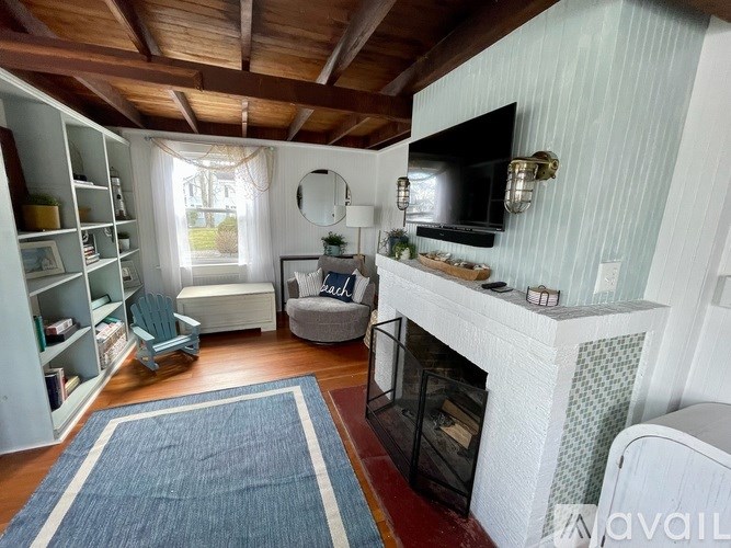 A living room with a fireplace and a blue rug.