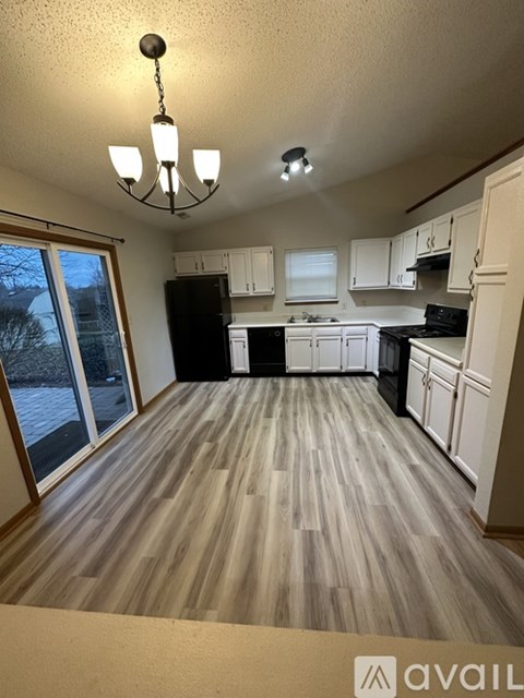 A kitchen with white cabinets and a wooden floor.