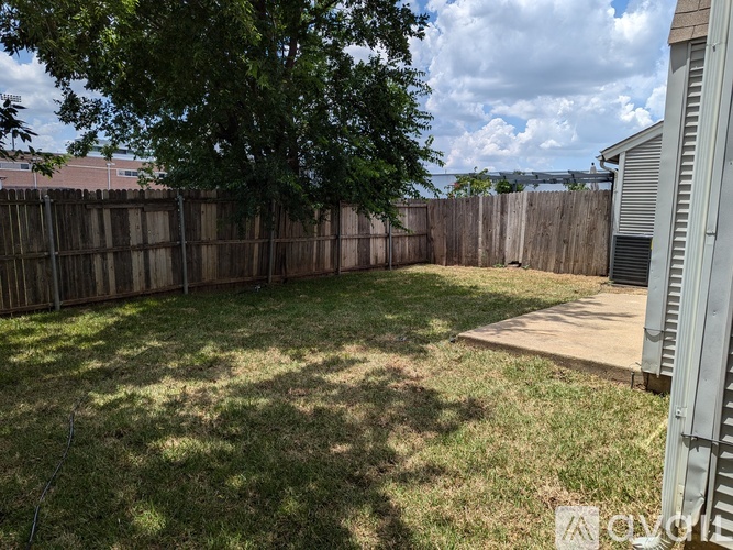 A backyard with a wooden fence and a tree.