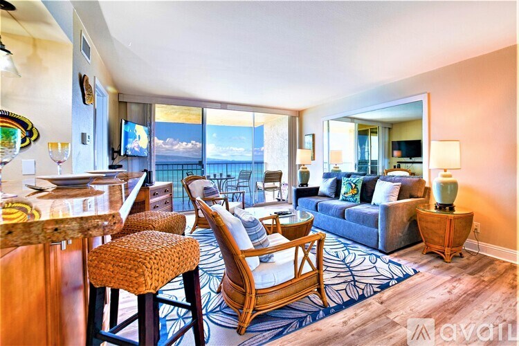 A living room with a bar area and a view of the ocean.