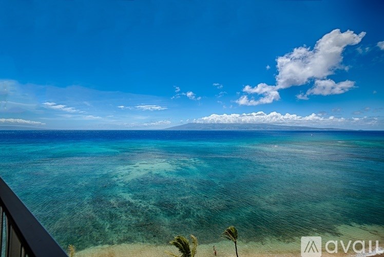 A beautiful beach view with clear blue water and a few clouds in the sky.