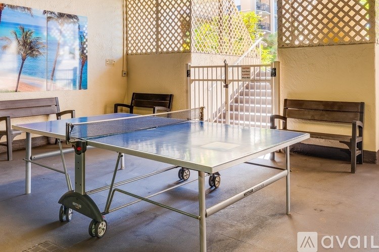 A ping pong table is in the middle of a room with a bench and a staircase.