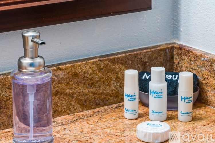 A bathroom sink with a soap dispenser and four bottles of lotion.
