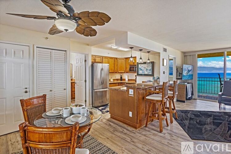 A kitchen with a dining table set for two and a fan.