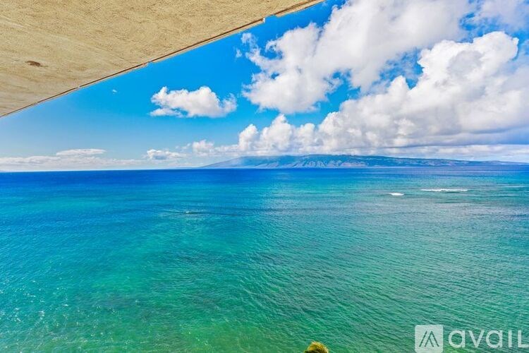 A beautiful beach with clear blue water and white clouds in the sky.