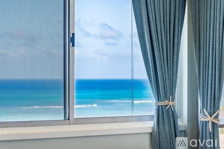 A window with a view of the ocean and a partly cloudy sky.