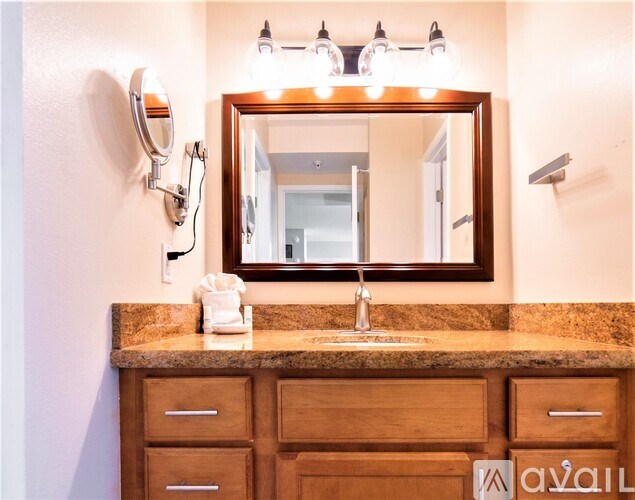 A bathroom vanity with a sink, mirror, and lighting fixtures.