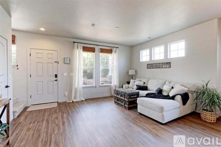A living room with a white couch and wooden floors.