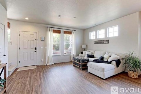 A living room with a white couch and wooden floors.