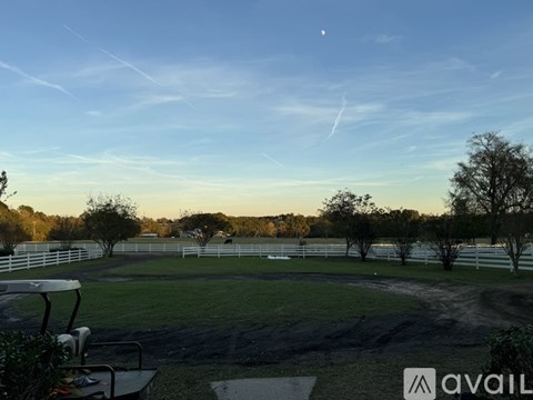 A field with a white fence and a clear sky.