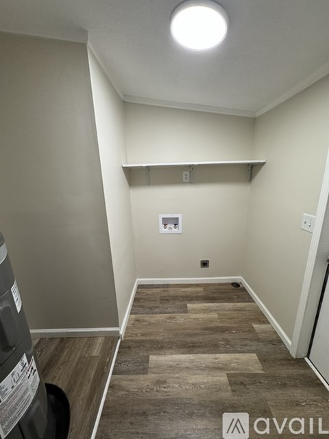 A hallway with a light on the ceiling and a trash can on the left.
