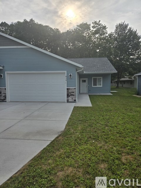 A blue house with a white garage door and a driveway leading to it.