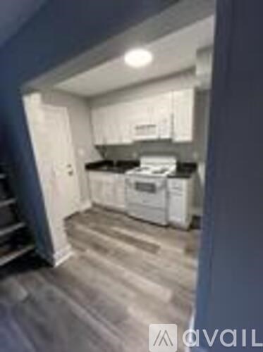 A kitchen with white appliances and wooden floors.