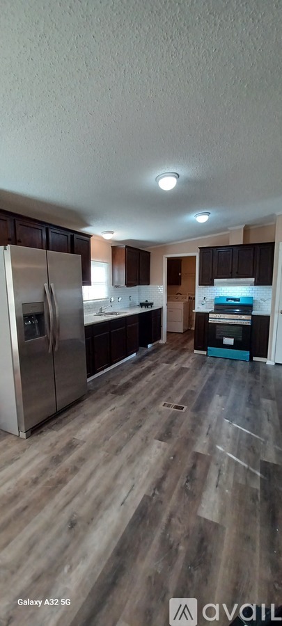 A kitchen with a refrigerator and wooden flooring.