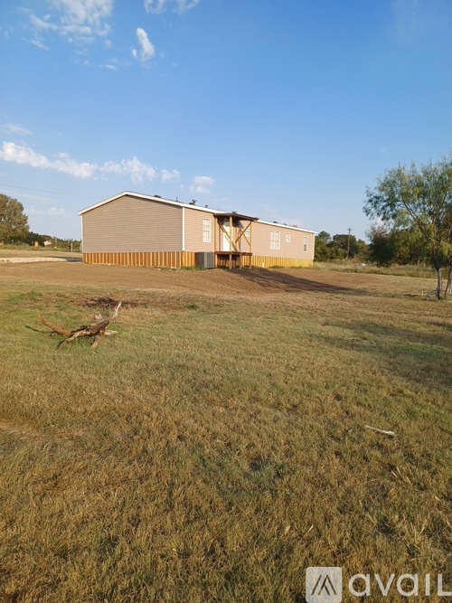 A large building with a grey roof is situated in a field.