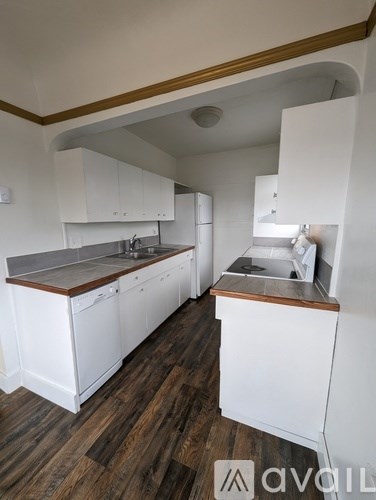 A kitchen with white cabinets and a wooden floor.