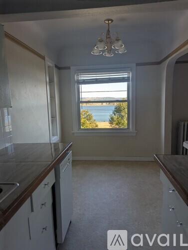 A room with two windows showing a view of a body of water and some trees.