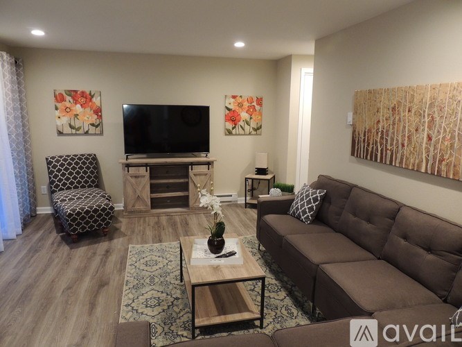 A living room with a brown couch, a chair, and a television.