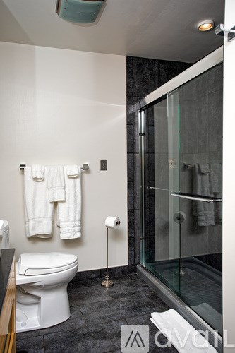 A white toilet sits in a bathroom next to a glass shower.