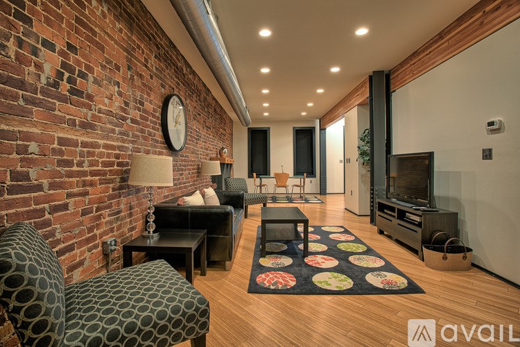 A living room with a brick wall and a patterned rug.