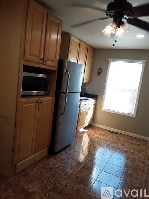 A kitchen with a refrigerator, microwave, and cabinets.