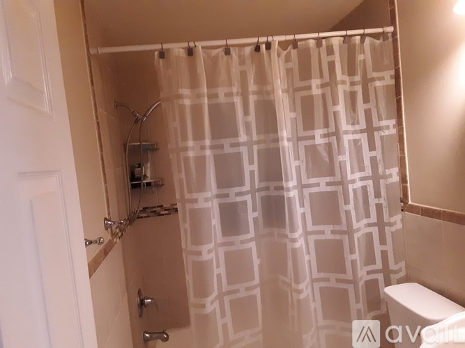 A white shower curtain with a geometric pattern hangs in a bathroom.